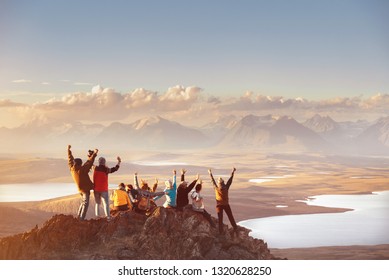 Große Gruppe glücklicher Freunde hat Spaß auf der Bergspitze und sieht sich das Bergtal an. Abenteuer- oder Reisekonzept