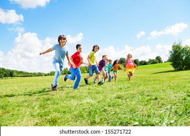 Large Group Of Happy Kids, Boys And Girls Running In The Park On Sunny Summer Day In Casual Clothes