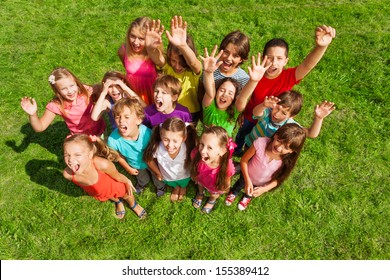 Large Group Of Happy Kids, Boys And Girls, About 10 Years Old Standing On The Green Grass Top View