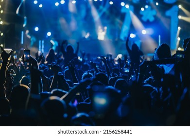 Large Group Of Happy People Enjoying Rock Concert And Clapping With Raised Up Hands. Hands Up With Pleasure From The Show. Music Festival.