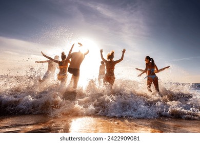 Large group of happy young friends are having fun and runs to swim at sunset sea beach. Tropical vacations concept - Powered by Shutterstock