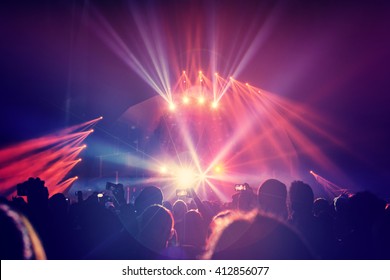 Large Group Of A Happy Young People Enjoying Concert, Having Fun Spending Time In A Night Club, Dancing In Bright Laser Beams, Men Partying, Celebrating Holidays