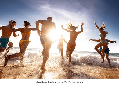 Large group of happy young tourists are having fun, runs and jumps at sunset sea beach. Tropical holidays concept - Powered by Shutterstock