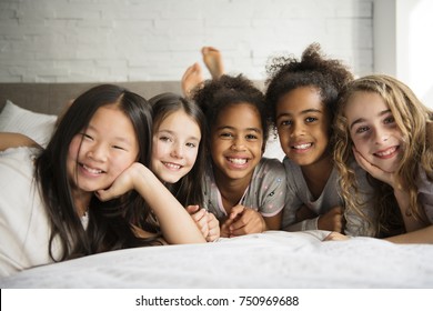 A large group of her friends taking goog time on bed