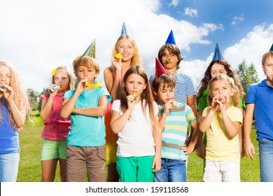 Large Group Of Kids Age 5 To 11 Outside On A Birthday Party Blowing Noisemakers Horns And Twisted Whistles