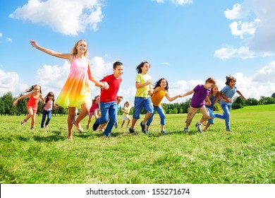 Large Group Of Kids, Boys And Girls Smiling And Running In The Park On Sunny Summer Day In Casual Clothes