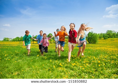 Large group of kids running in the dandelion spring field