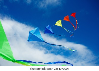 Large group of many beautiful colorful kites fly on the string over blue sky with clouds - Powered by Shutterstock