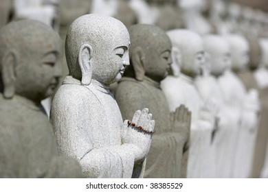 Large Group Of Meditating Buddhas. Focused On White Statue With Rosary.