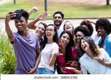 Large group of multi ethnic young adults taking crazy selfie with phone outdoor in summer in city