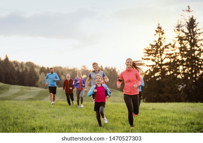 A Large Group Of People Cross Country Running In Nature.