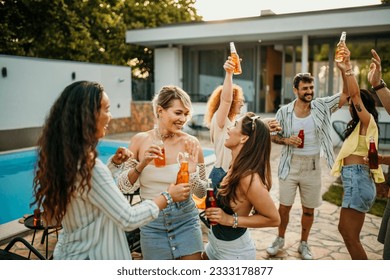 A large group of people gather around a poolside, pouring their favorite cocktails from the bottles and enjoying the refreshing beverages.	 - Powered by Shutterstock