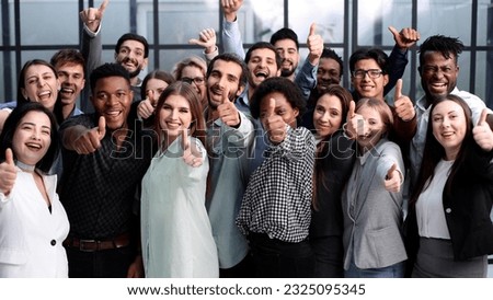 Large Group of people standing together in studio showing thumbs up