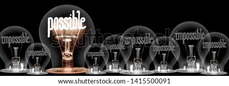 Large group of shining and dimmed light bulbs with fibers in a shape of Impossible and Possible words isolated on black background; concept of Motivation, Success and Change