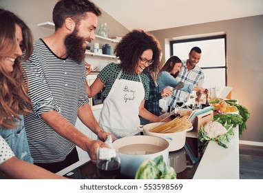 Large group of six happy friends preparing food for a pasta cooking class at table at home or in a small culinary school - Powered by Shutterstock