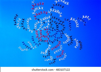 Large Group Of Skydivers Flying In Formation Of Flower Against Blue Sky