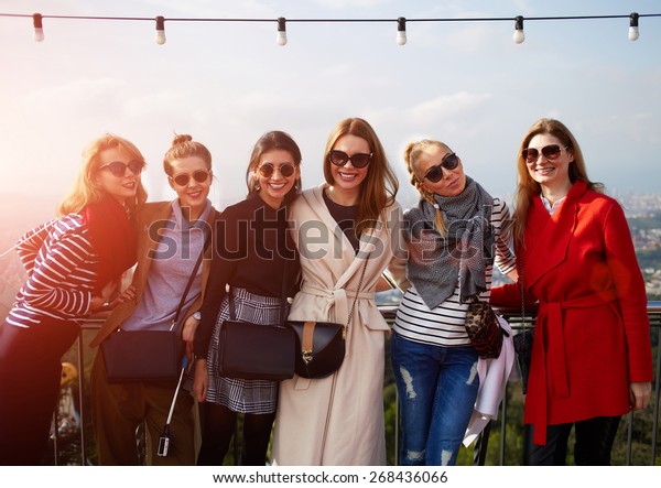 Large group of smiling girlfriends staying\
together at sunny day and looking at camera, vacation travel\
holidays wit best friends, smiling\
women