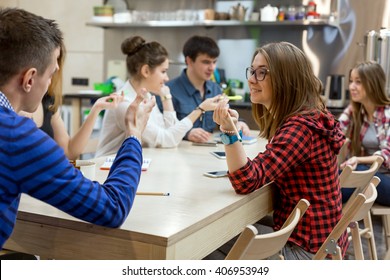 Große Gruppe von Schülerinnen und Schülerinnen, die sich am Wood Table des Campus Chat Room entspannen und dabei Spaß haben