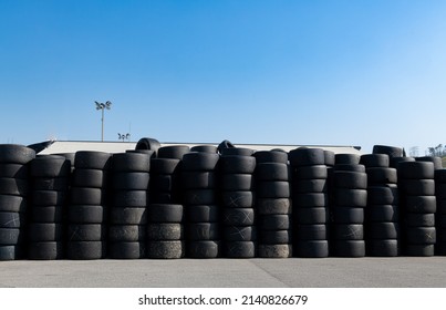 Large Group Of Used Old Slick Racing Tire Stacked Against Blue Sky