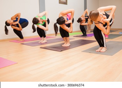 Large Group Of Women Holding The Chair Pose During Their Yoga Class. Lots Of Copy Space