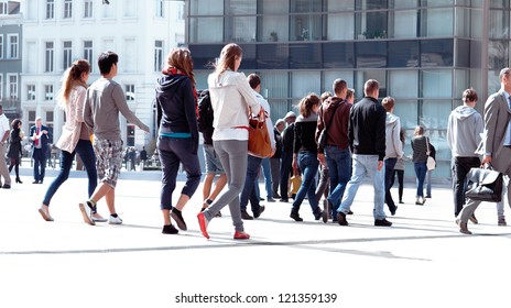 A large group of young men and women walking. The urban landscape.