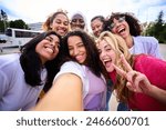 Large group of young smiling multiracial only women taking selfie photo looking at camera outdoor. Cheerful beautiful female friends with positive face emotions. Girls Power, diversity and community