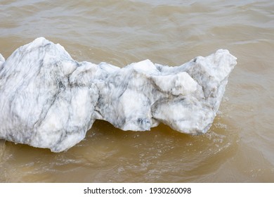 Large Gypsum Rock Or Stone Surrounded By Water. Big Wet Calcite Washed In The River Shore With Lots Of Waves. Semi Precious White Gem Deposit Or Mining