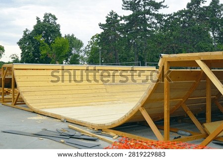 Large half-pipe ramp within developing skate park. Demonstrates specialized sports infrastructure development, skateboarding facility construction, action recreation venue design, and custom-built wooden structures.