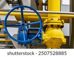 A large handwheel on a valve connected to a large pipe, painted yellow to possibly indicate a gas pipe