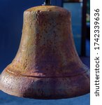 A large hanging bell is rusted from exposure to the elements