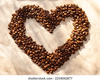 A Large heart made of coffee beans on craft paper. Warm light. Top view. Valentine's Day Postcard. - Shutterstock ID 2254042877