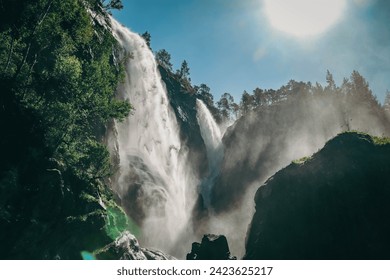 Large Hesjedalsfossen waterfall next to the road in Hordaland, Norway. Long exposure of flowing water. Water cascading down the stones in the forest. Fairy-tale and mysterious atmosphere, no people. - Powered by Shutterstock