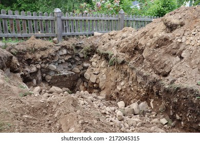 Large Hole Of Dirt Sand And Rocks In The Ground After Excavation Digging Up The Sewage System To Change Pipes Underground In The Backyard Outside The Residence Expensive Renovation