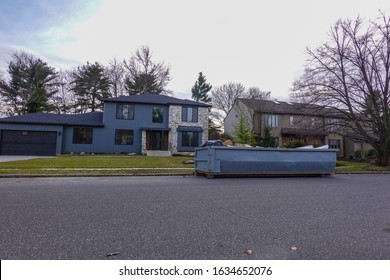 Large home on a residential street with a long blue dumpster on the road in front