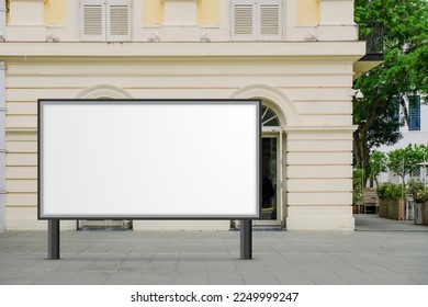 Large horizontal blank advertising poster billboard banner mockup in front of building in urban city; digital light box display screen for OOH media. 12 sheet out-of-home