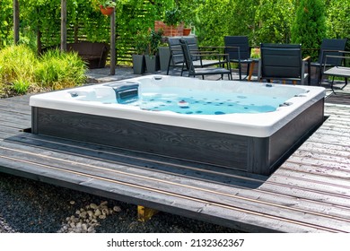 Large hot tub embedded in the backyard terrace. A sunny summer's day in the shelter of a green garden. Everyday luxury and relaxation in your own backyard. Spa complex, vacation and traveling concept. - Shutterstock ID 2132362367