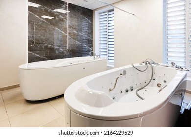 Large hydromassaging bathtub near mirror wall at spa resort