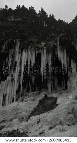 Large icicles dangling from rocks at middle cove beach in Canada St. John’s Newfoundland and Labrador with lots of rocks  