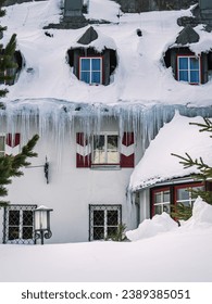 Large icicles and snow cover on a hotel building during winter in a ski resort, Carinthia, Austria