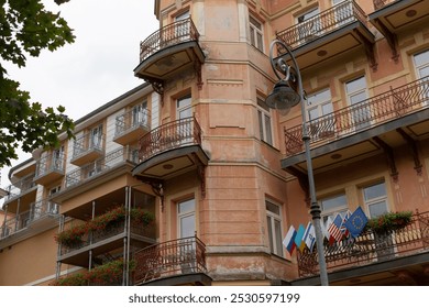 A large and impressive building adorned with multiple balconies and flags proudly displayed flapping in the breeze on each balcony