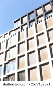 A large and impressive building featuring numerous windows, with a vibrant blue sky beautifully set against its backdrop, emphasizing its design