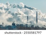 A large industrial city with a thick cloud of smoke billowing from a factory. The smoke is so thick that it is difficult to see the sky. Concept of pollution and industrialization