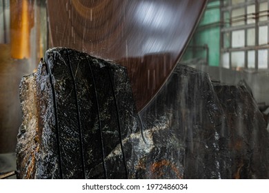 Large industrial cutting machine cuts gray granite stone into slabs. power industrial stonecutter equipment. Huge saw blade rotates at high speed. High rpm. Water pouring over stone to cool cutting - Shutterstock ID 1972486034