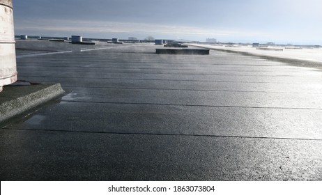 Large industrial flat roof with sun evaporating the rainwater from the surface