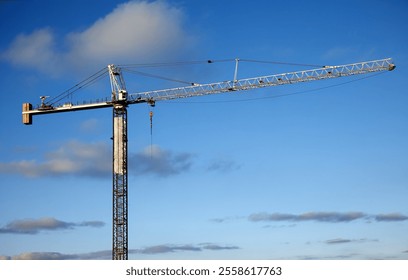 Large industrial tower crane used for heavy lifting on a construction site with a clear blue sky background. - Powered by Shutterstock