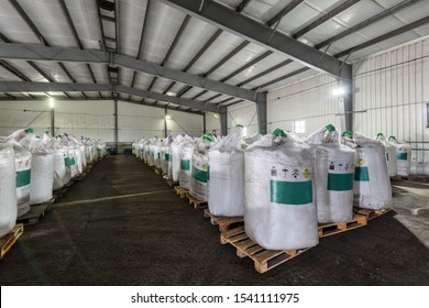 Large industrial warehouse of chemicals. Large white bags filled with powder are arranged in long rows.