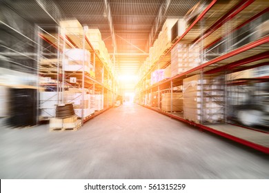 Large industrial warehouse. Long shelves with a variety of boxes and containers. The effect of motion blur. Bright sunlight.