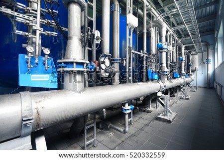 Large industrial water treatment and boiler room. Shiny steel metal pipes and blue pupms and valves.  Industry, technology, special equipment, pure drinking water, biotechnology, chemistry, ecology