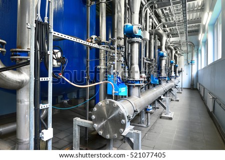 Large industrial water treatment and boiler room. Shiny steel metal pipes, blue pumps and valves, close-up. Industry, technology, special equipment, biotechnology, chemistry, ecology, environment