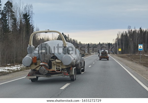 A large inflatable\
boat rides a car trailer on the track. Dangerous overtaking and\
driving on the road